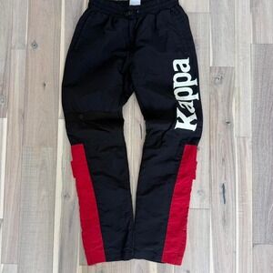 Kappa black track pants with red stripes and white logo. Size: S
